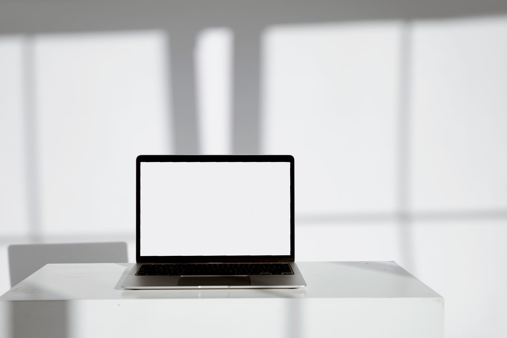 Espacio creativo digital con portátil y geometría arquitectónica de luz y sombra